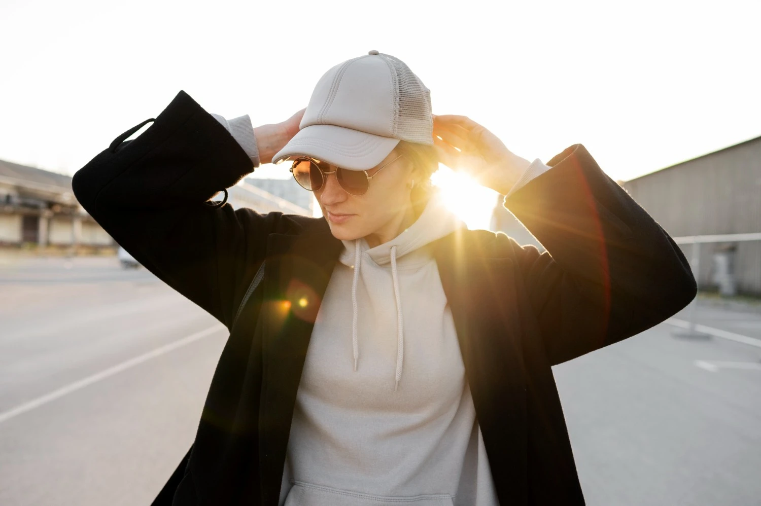 Una persona con gafas de sol y una gorra de béisbol gris parada al aire libre al atardecer con un destello de lente en el fondo Una persona con gafas de sol y una gorra de béisbol gris parada al aire libre al atardecer con un destello de lente en el fondo