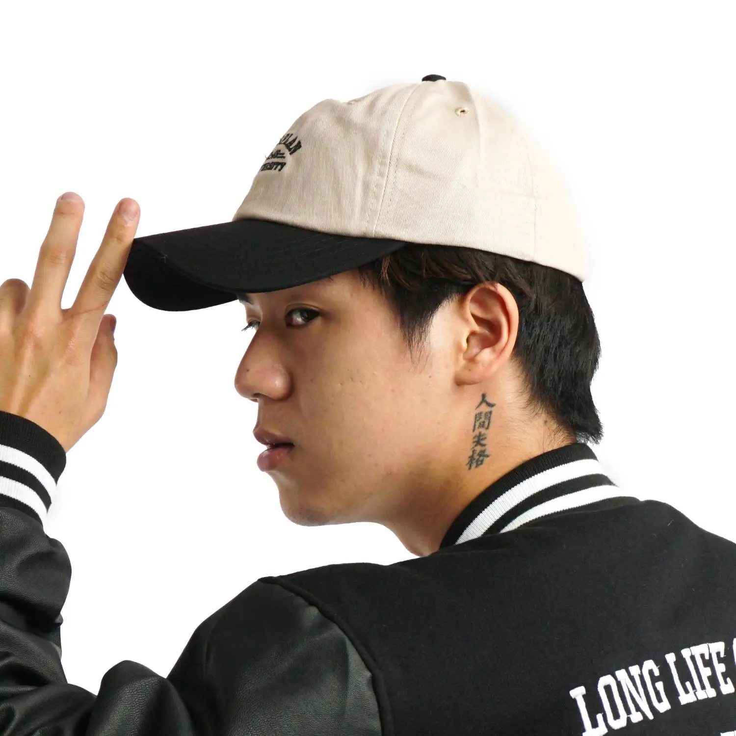 Un joven haciendo el signo de la paz con una gorra de béisbol de color beige claro y visera negra.