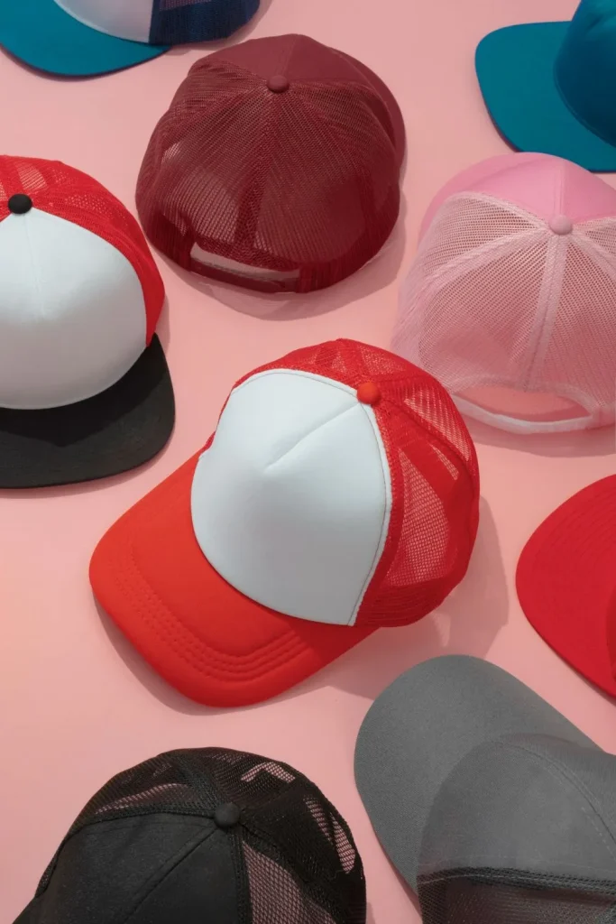 Pembe bir arka plan üzerinde çeşitli renkler ve açılar sergileyen çeşitli renkli örgü kamyoncu şapkaları