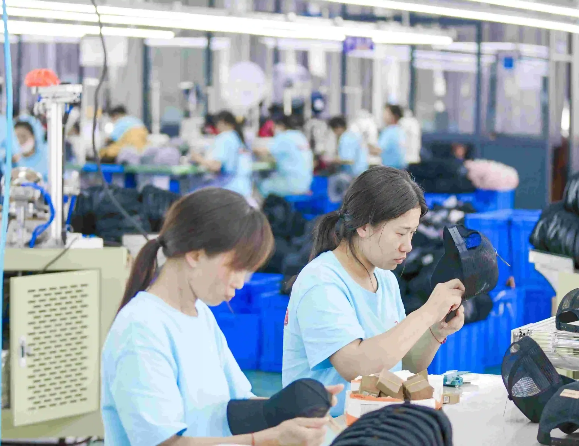 Factory quality inspectors reviewing finished caps during production