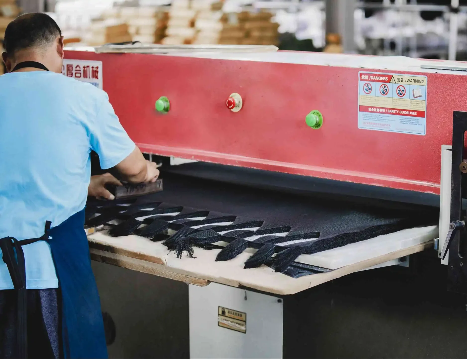 Factory operator cutting black cap panels after material approval