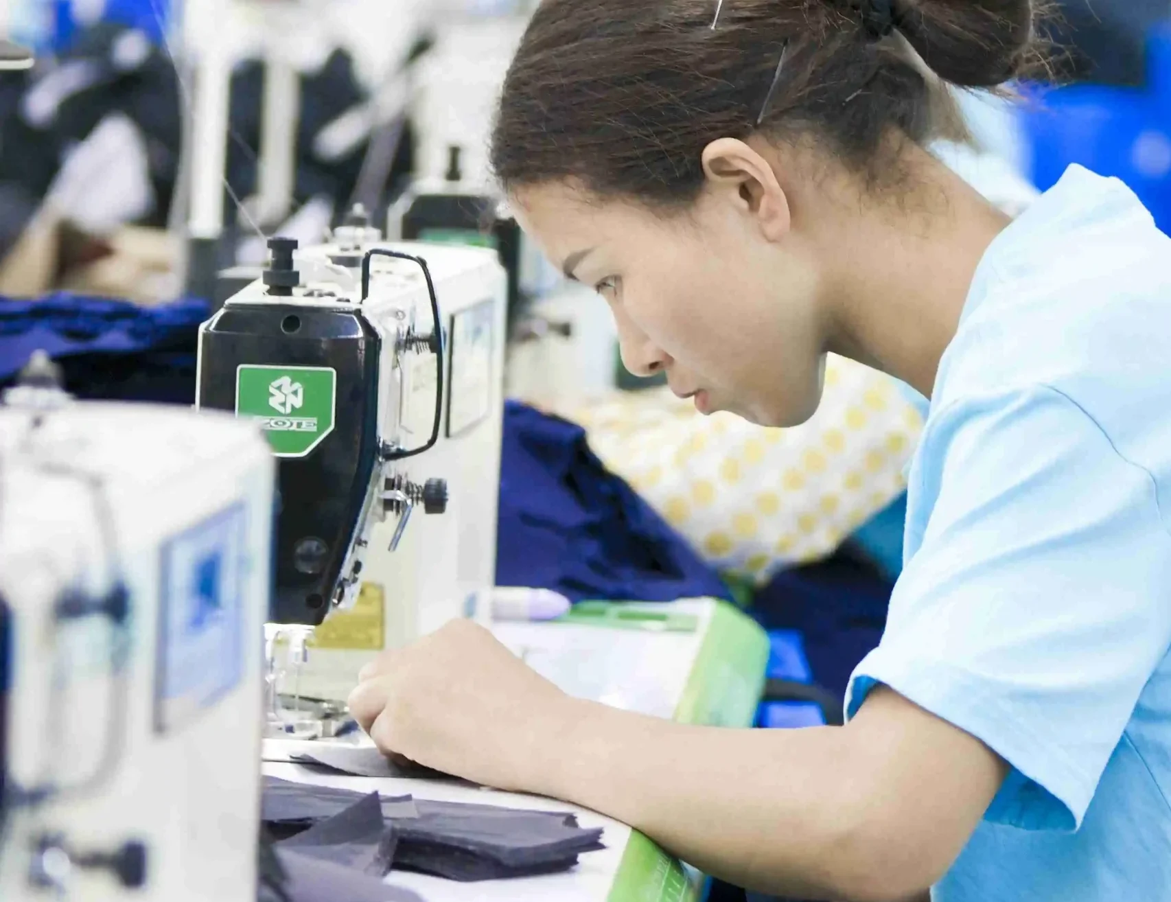 Factory operator sewing cut cap panels during production
