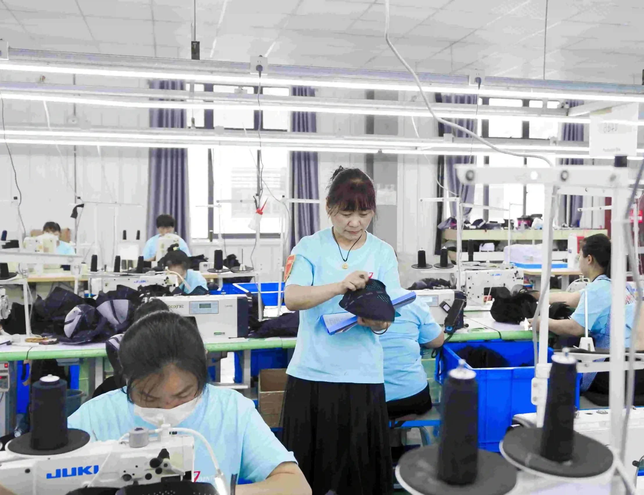 Factory inspector reviewing a semi-finished cap during sewing production