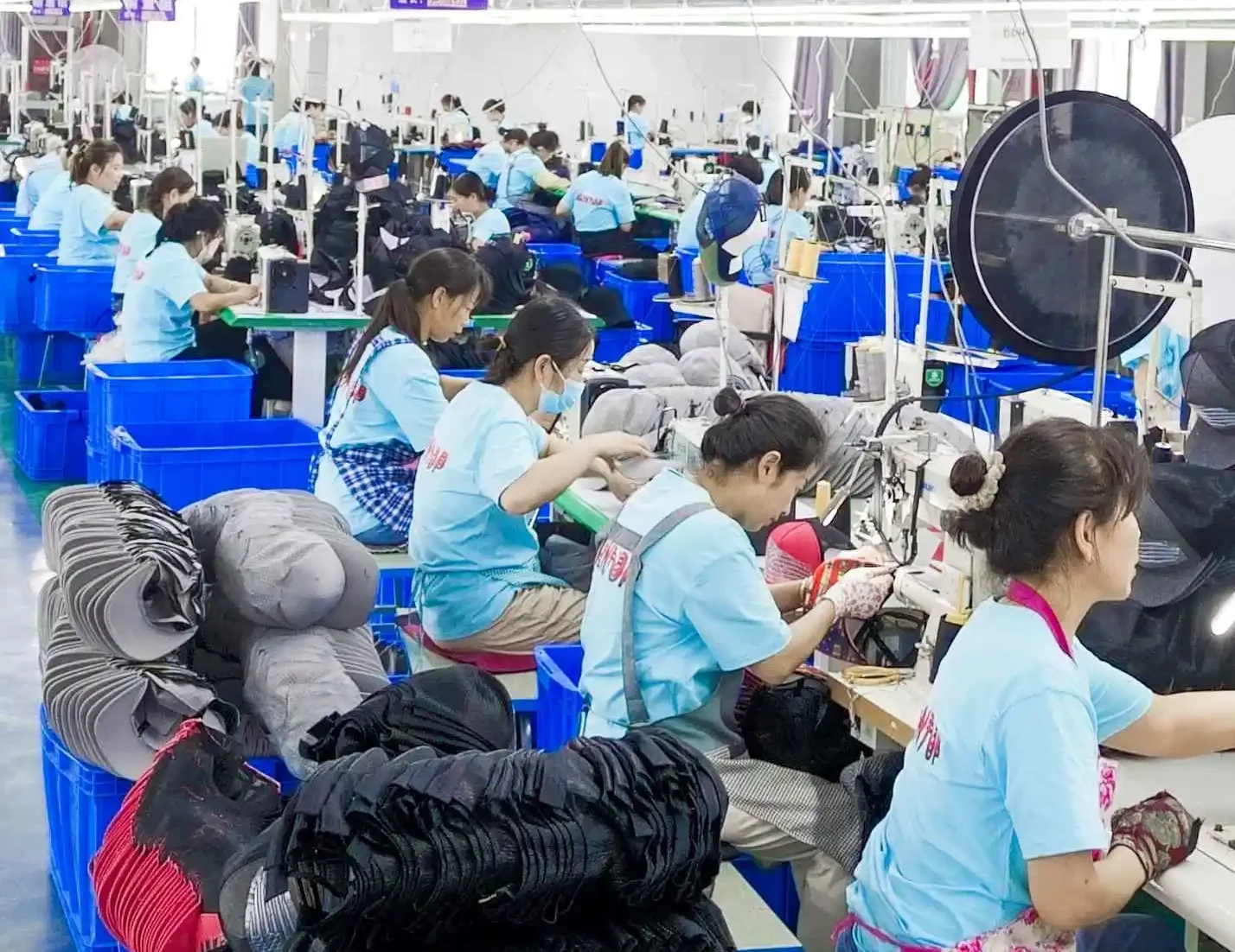 Factory operators stitching sweatbands into caps during production