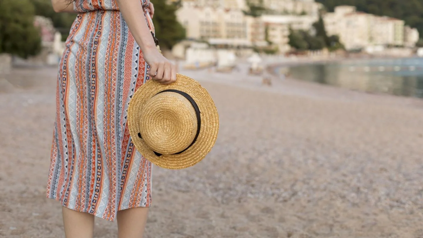 Woman holding a straw hat on a beach Woman holding a straw hat on a beach