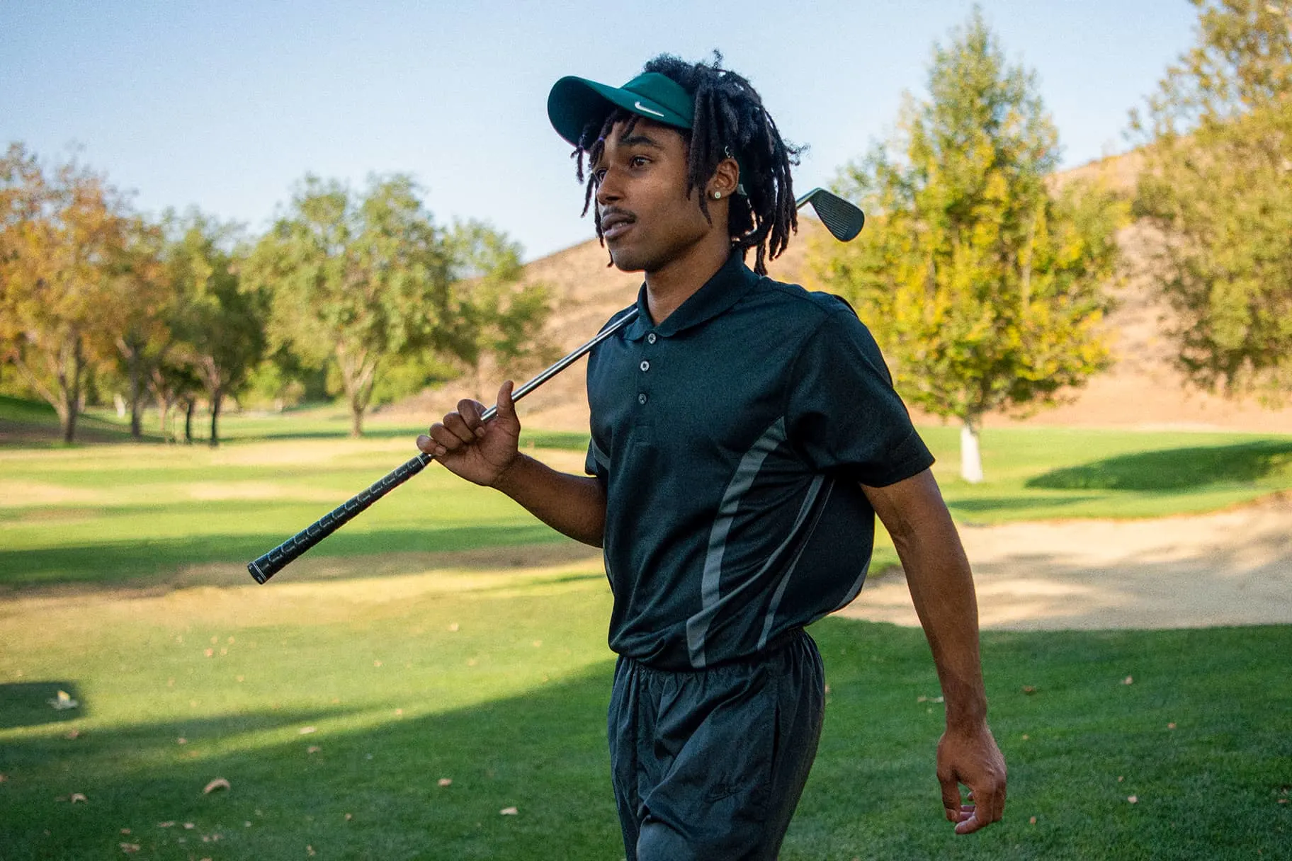 Man wearing a green visor carrying a golf club - Ultimate Guide to Golf Hat Styles - JoinTop | Custom Hat & Cap Manufacturer | OEM & ODM Headwear Factory - JoinTop | Custom Hat & Cap Manufacturer | OEM & ODM Headwear Factory Man wearing a green visor carrying a golf club