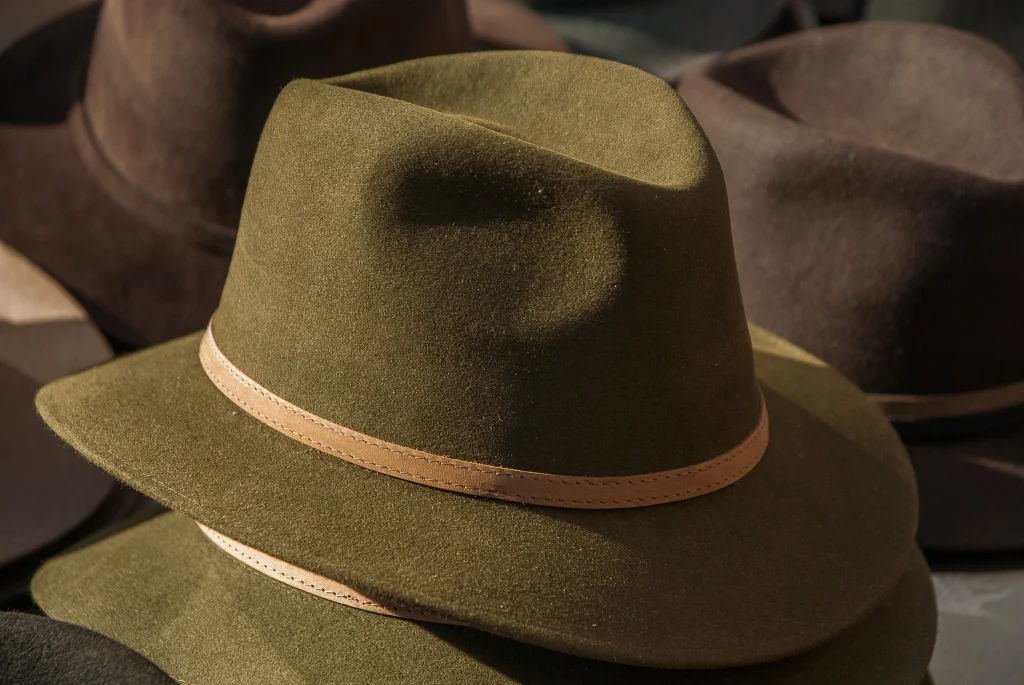 Olive green fedora with tan band resting on display