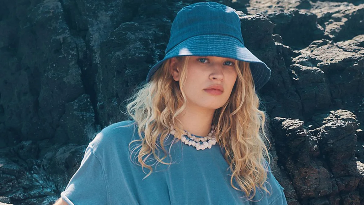 Woman in a blue bucket hat standing against rocks