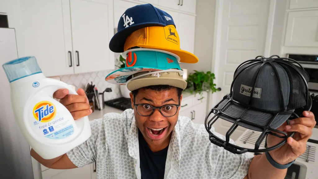 Hombre sosteniendo una jaula para gorras y detergente con sombreros apilados