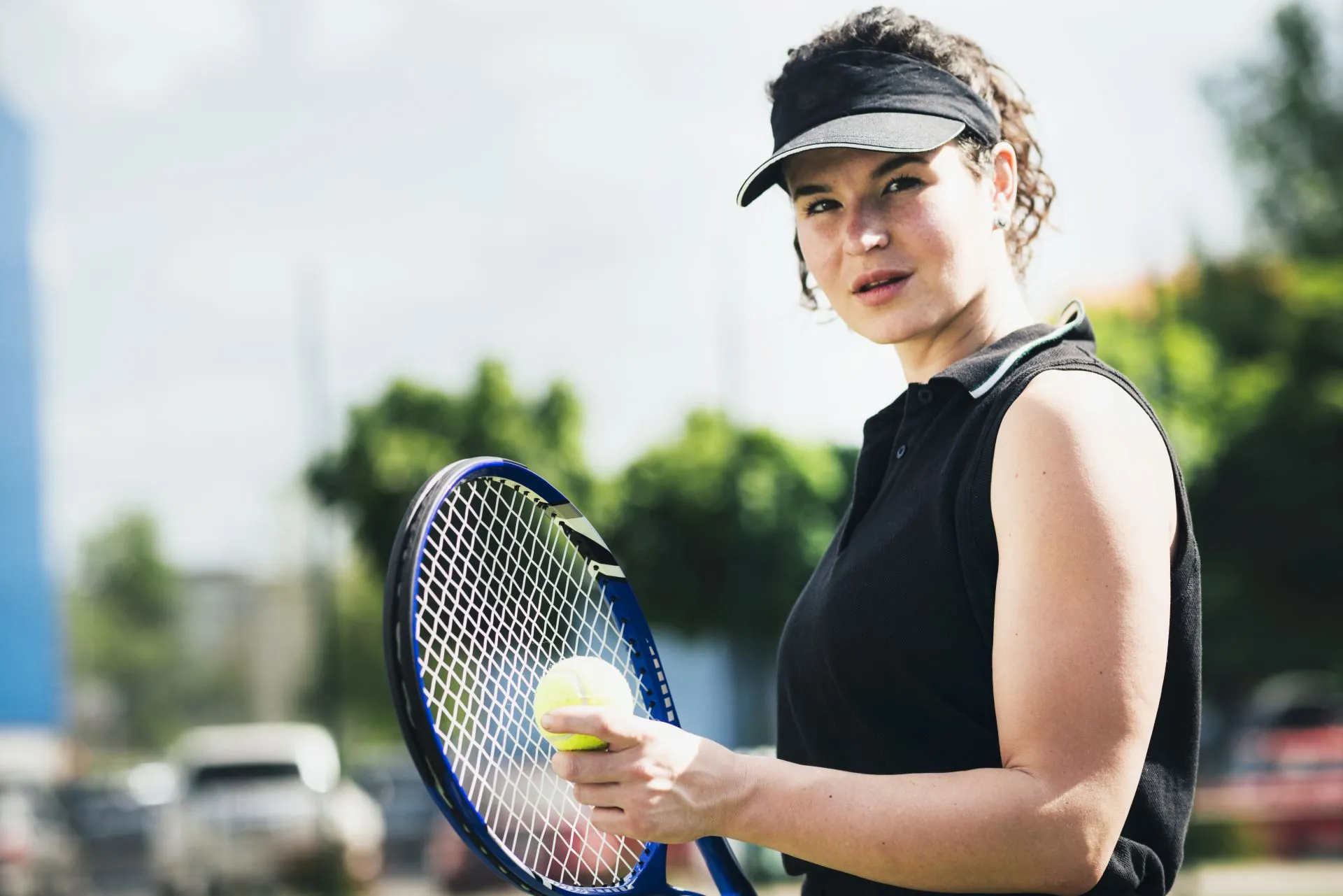 Femme tenant une raquette de tennis et une balle