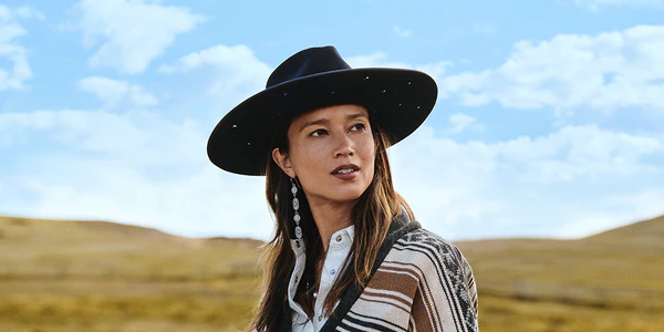 Woman in a studded black hat outdoors under a blue sky