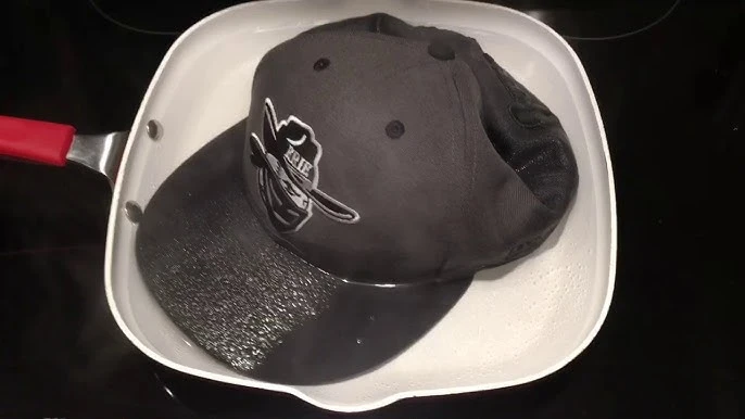 A cap soaking in water on a stovetop for reshaping