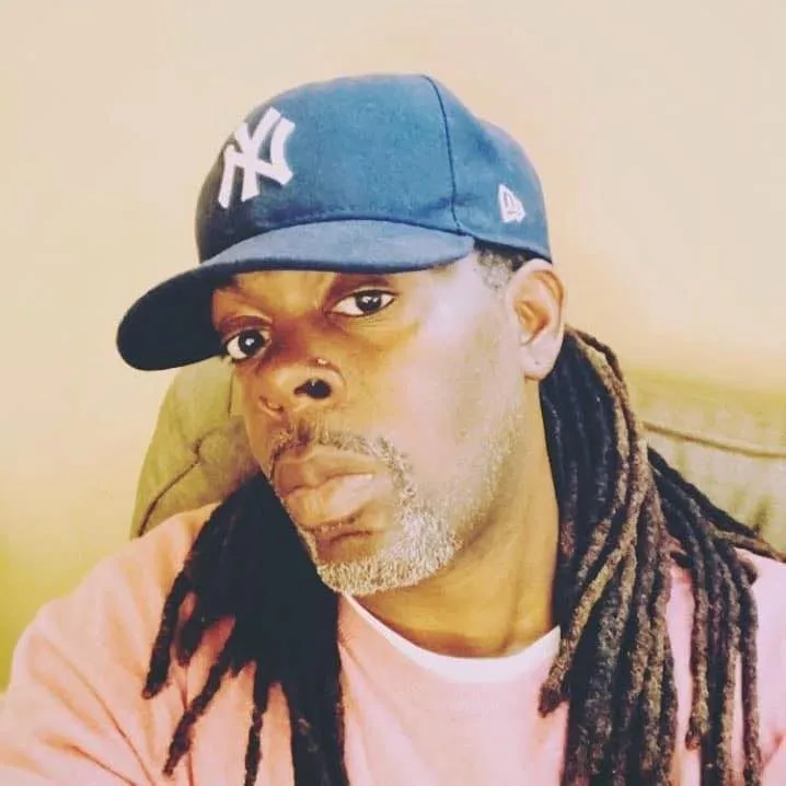 A man with dreadlocks wearing a Yankees hat