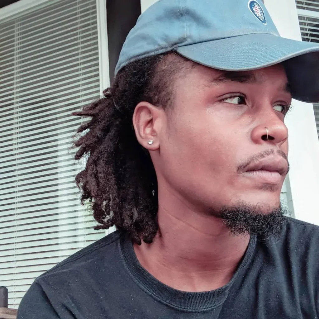 Un hombre con rastas que lleva una gorra de béisbol.