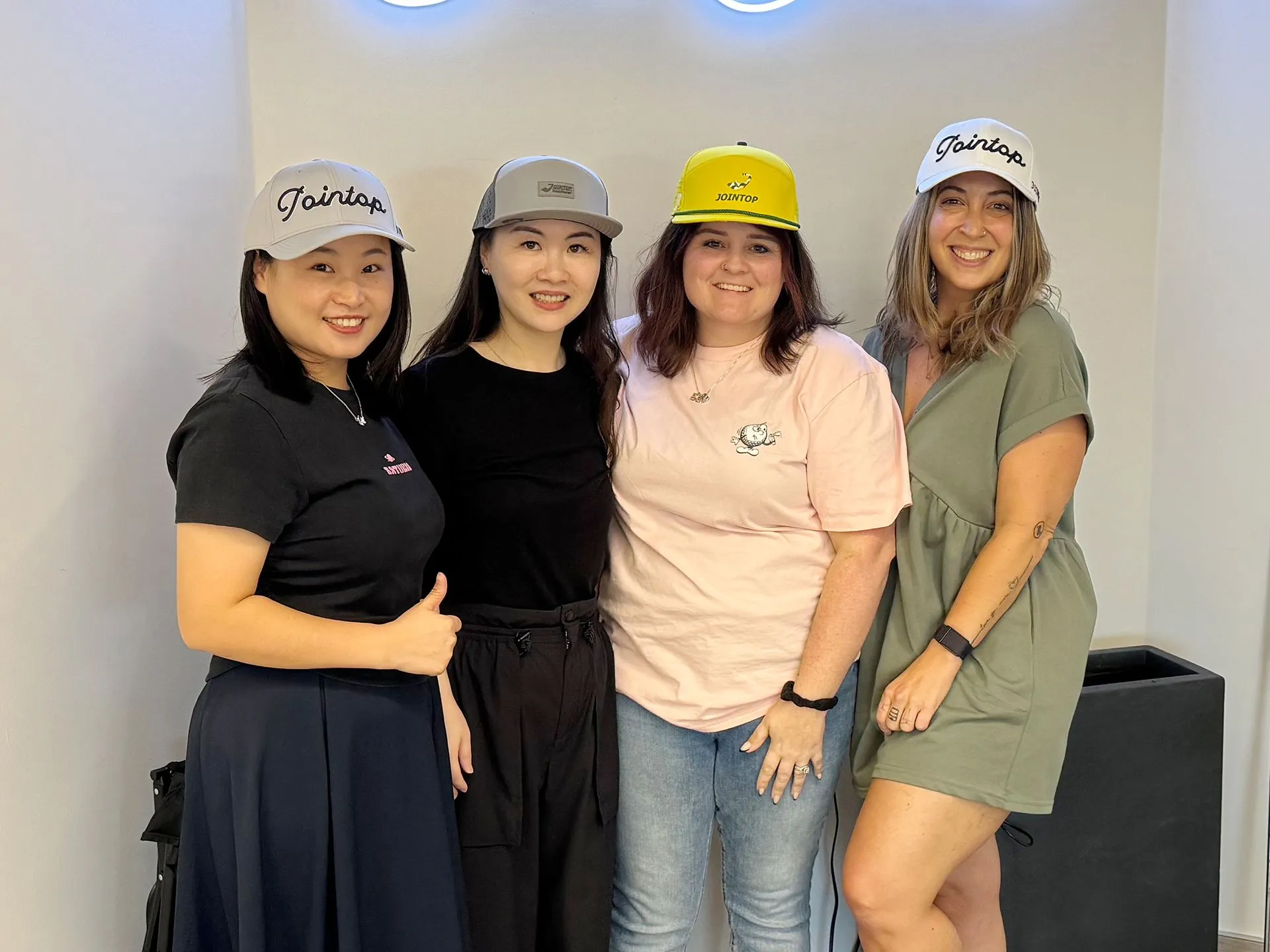 Jointop team showcasing branded caps in a group photo
