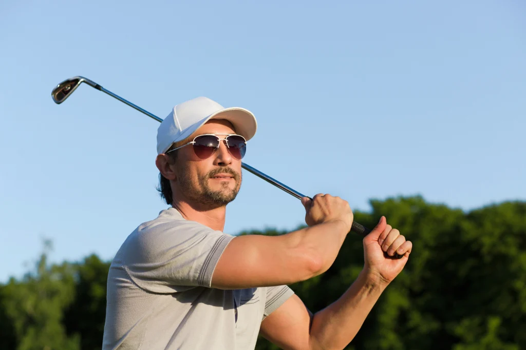 young golfer hitting shot with iron mature man sunglasses enjoing professional game green course