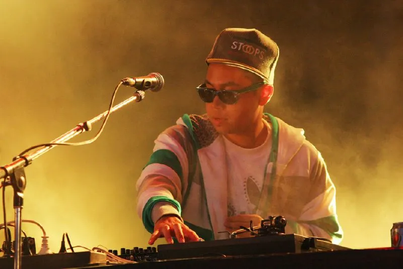 A DJ wearing a zip up hoodie and checkerboard frame sunglasses A DJ wearing a zip up hoodie and checkerboard frame sunglasses