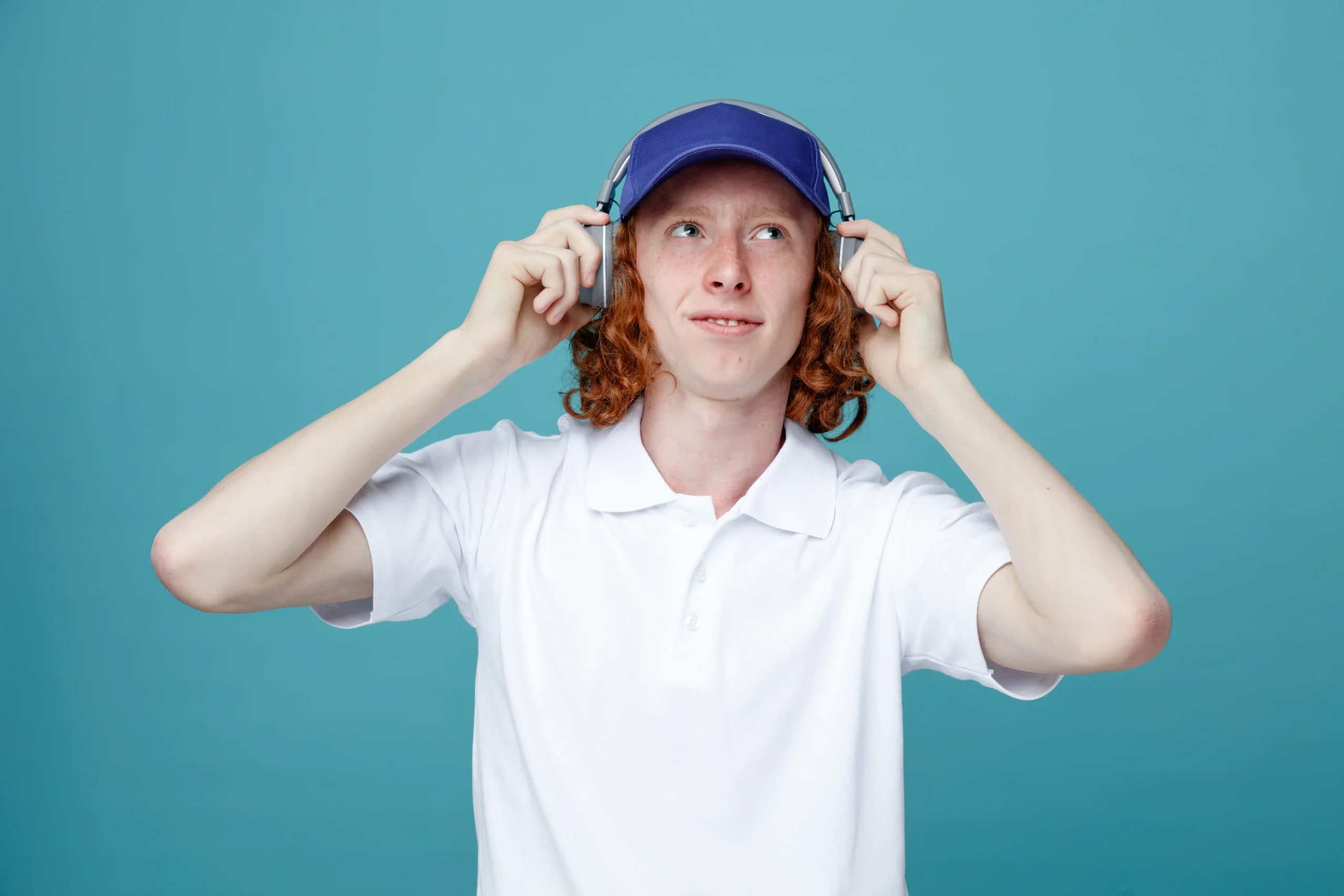 Chico guapo joven complacido con gorra y auriculares aislados sobre fondo azul Chico guapo joven complacido con gorra y auriculares aislados sobre fondo azul