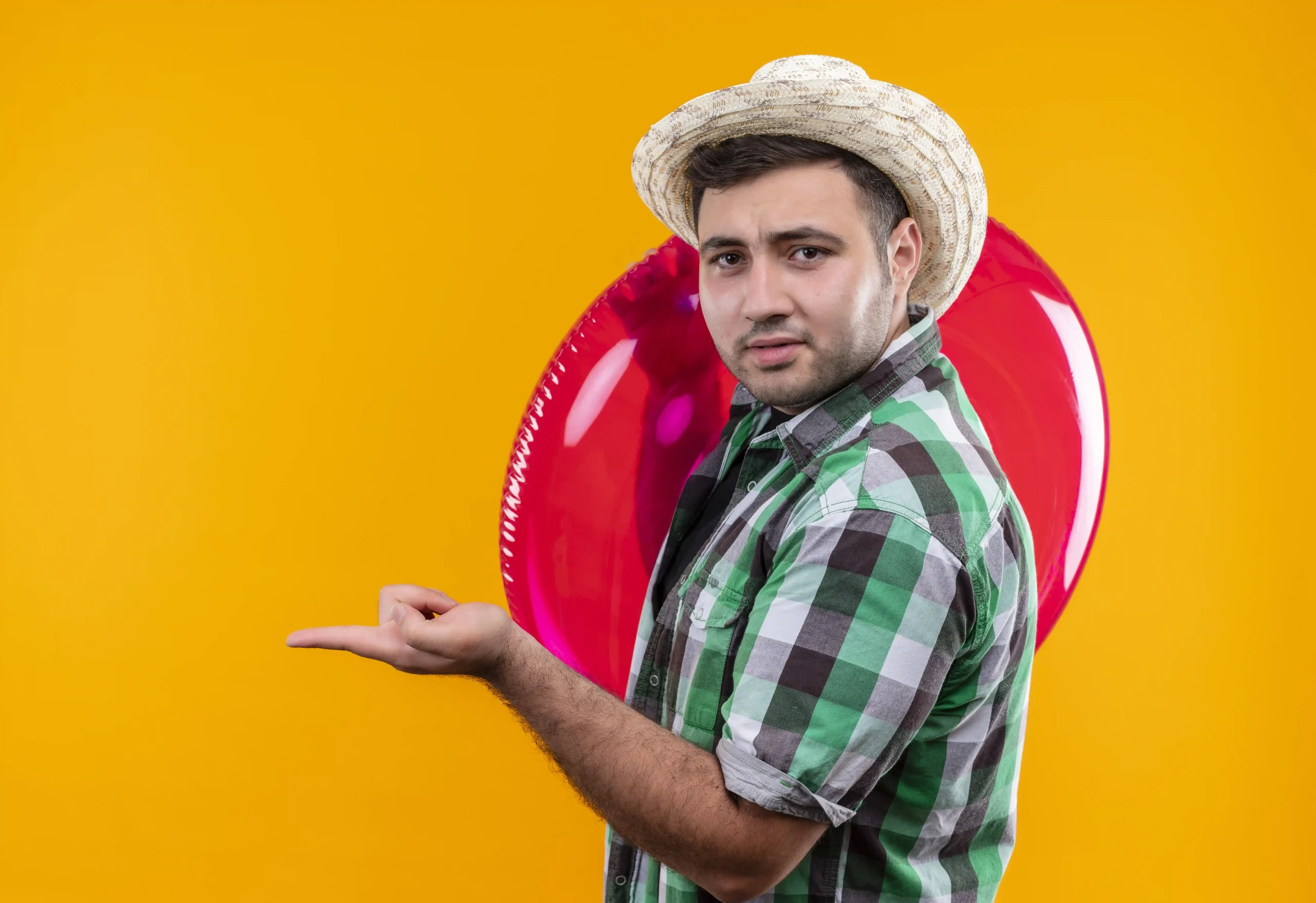 young traveler man checked shirt summer hat holding inflatable ring pointing with finger somewhere c young traveler man checked shirt summer hat holding inflatable ring pointing with finger somewhere c