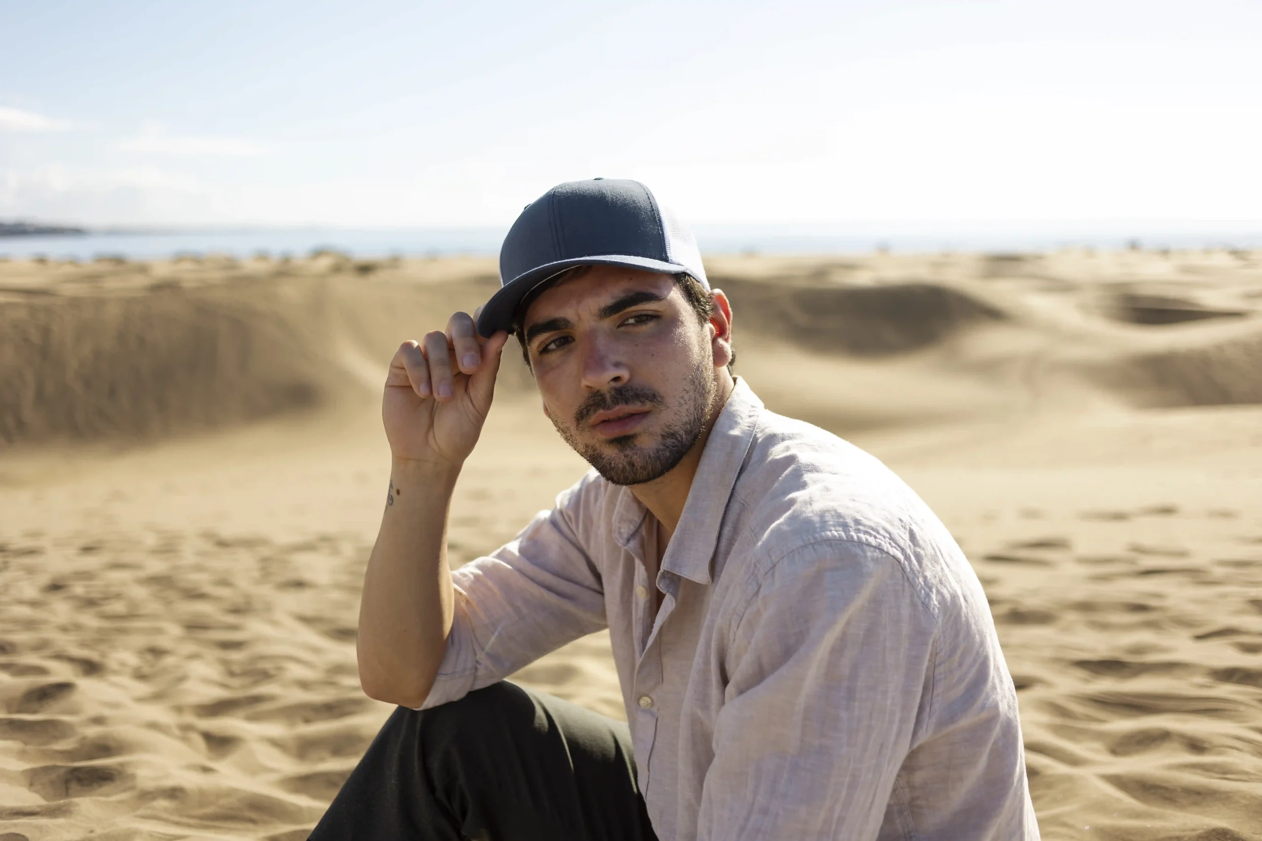 トラッカーハットをかぶった砂漠の男性（ミディアムショット）