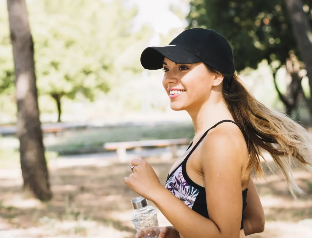side view fitness young woman running with water bottle park