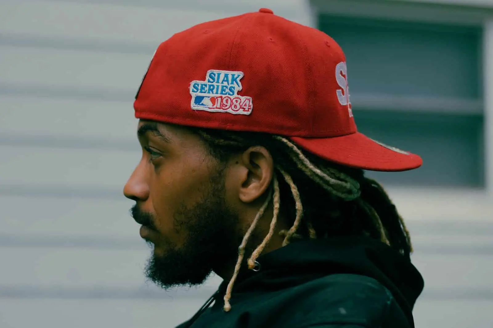 Man with dreadlocks wearing red snapback hat
