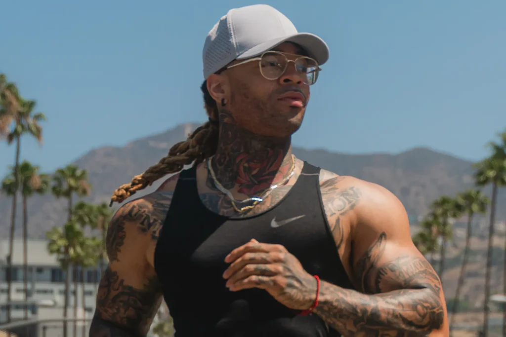Hombre tatuado con gorra gris negra corriendo