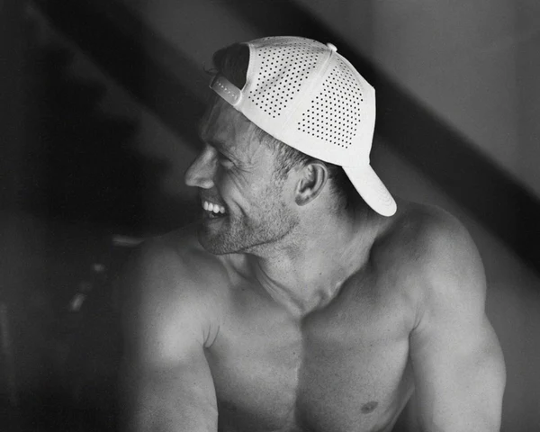 Мужчина улыбается в белой перфорированной влагоотводящей шапке