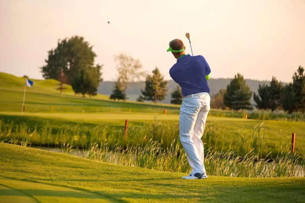A man in a golf cap making a golf swing