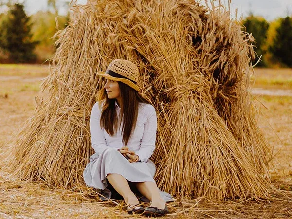 Woman wearing straw hat sitting by haystack Woman wearing straw hat sitting by haystack